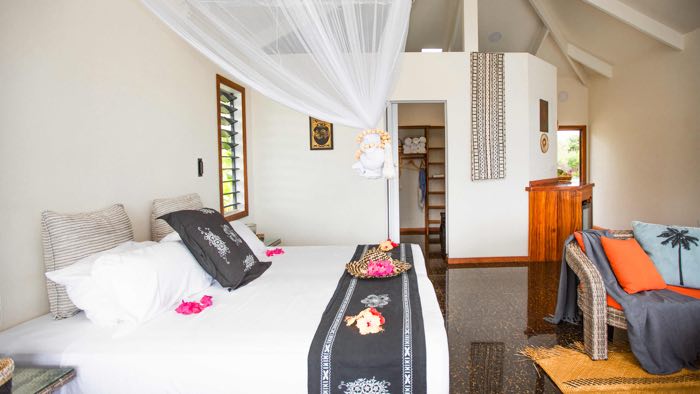 luxurious overwater villa interior with a spacious bed, stylish furnishings, and large glass doors opening to a deck