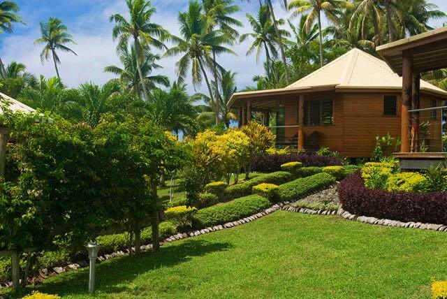cozy studio villa with a neatly made bed, wooden furniture, and tropical decor. Large windows let in natural light, creating