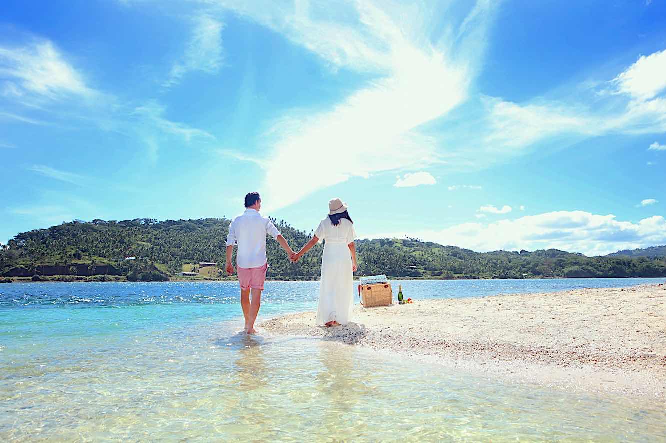A couple walking hand-in-hand along a sandy beach at La Dolce Vita Holiday Villas Fiji